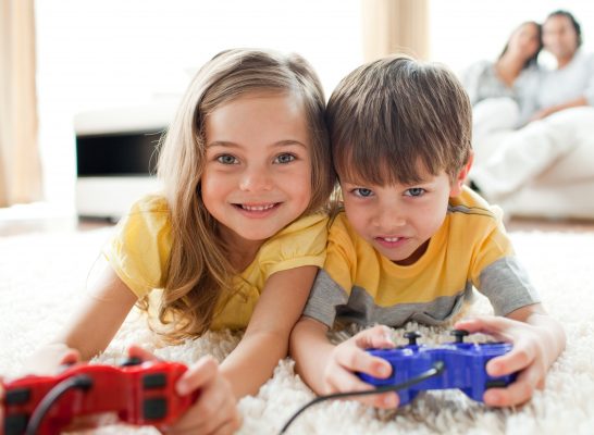 girl and boy playing on console smiling