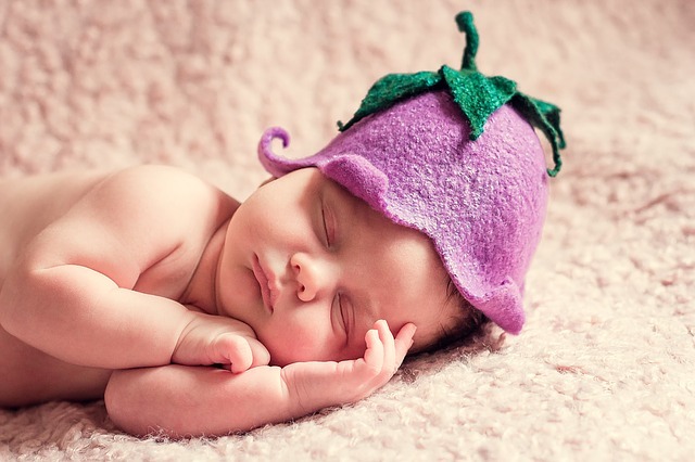 newborn baby wearing purple flower hat