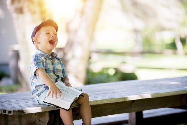 jeune garçon riant en lisant un livre 